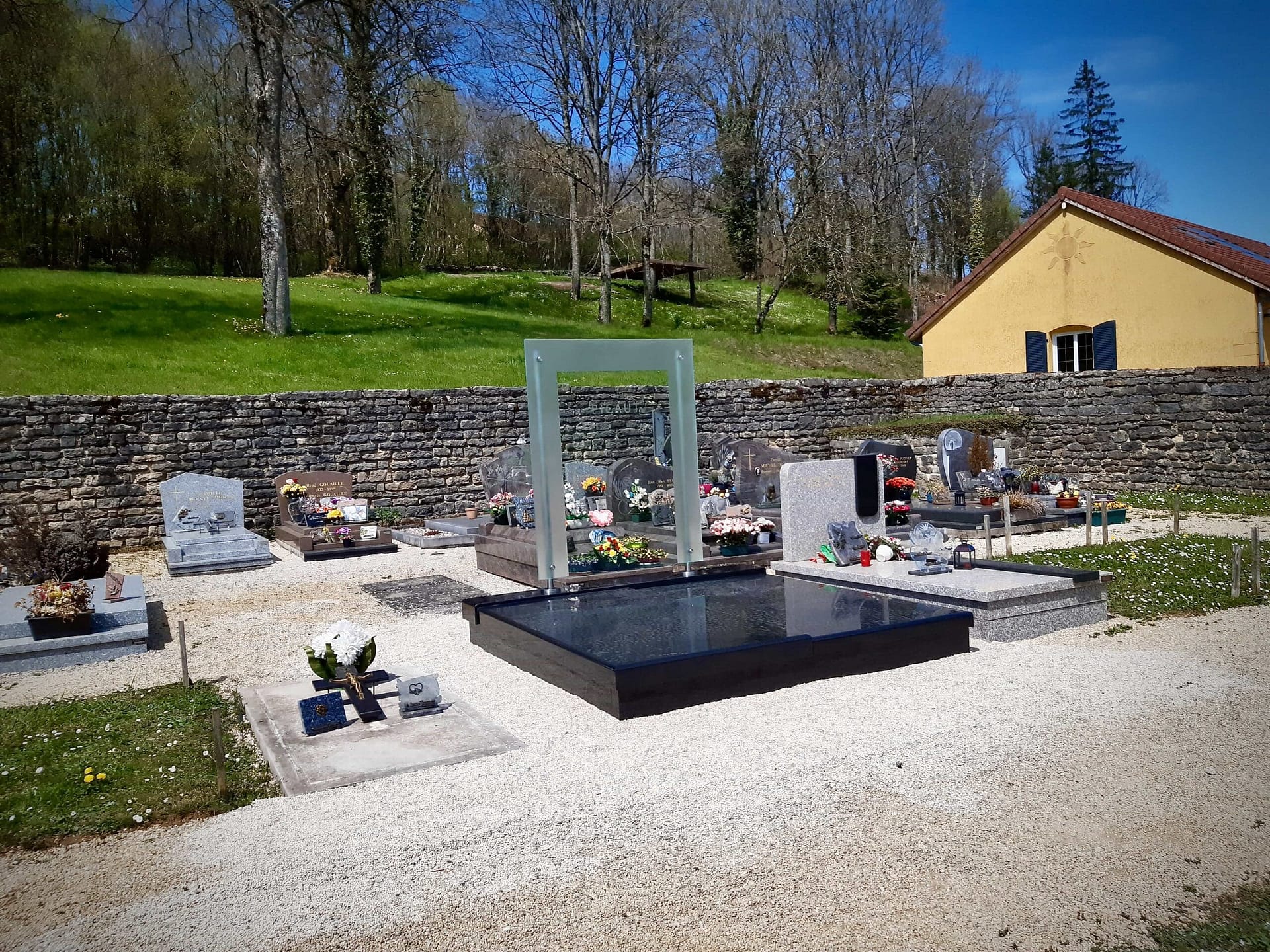 La stèle en verre devant le mur du cimetière