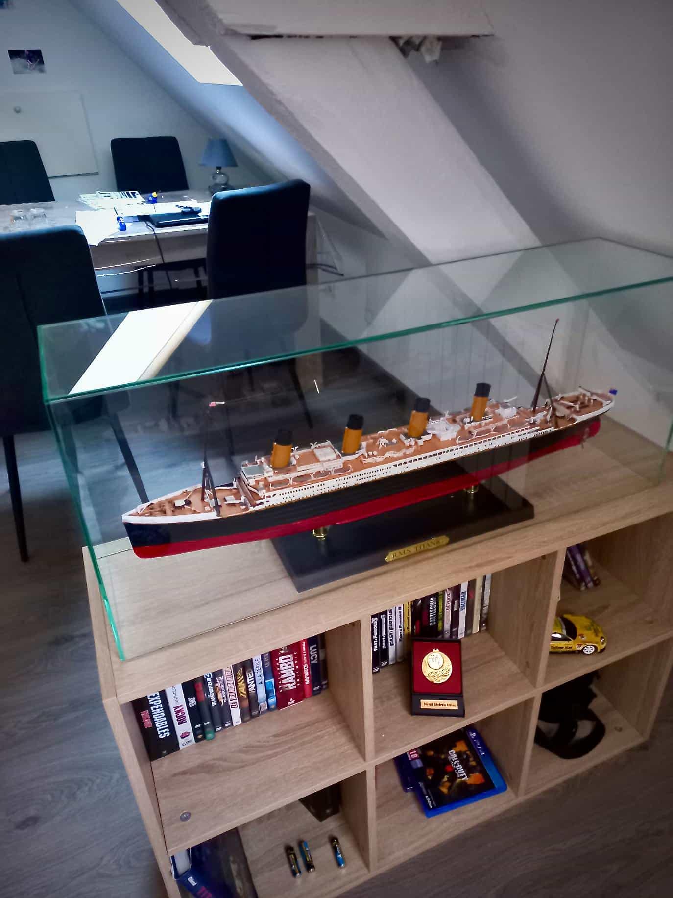 Caisson en verre clair protégeant une maquette de paquebot sur un meuble en bois