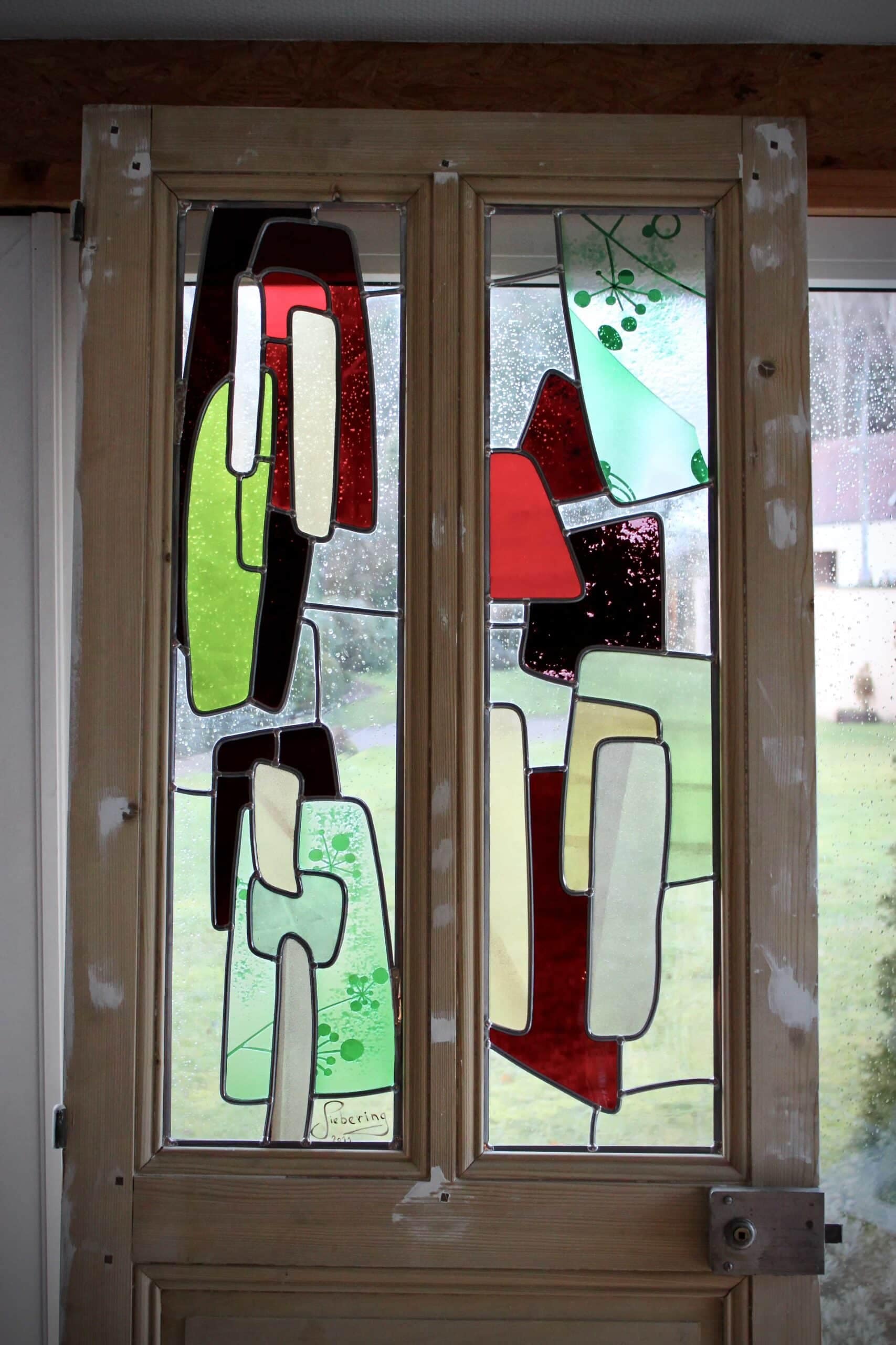 La porte en bois et ses deux vitraux