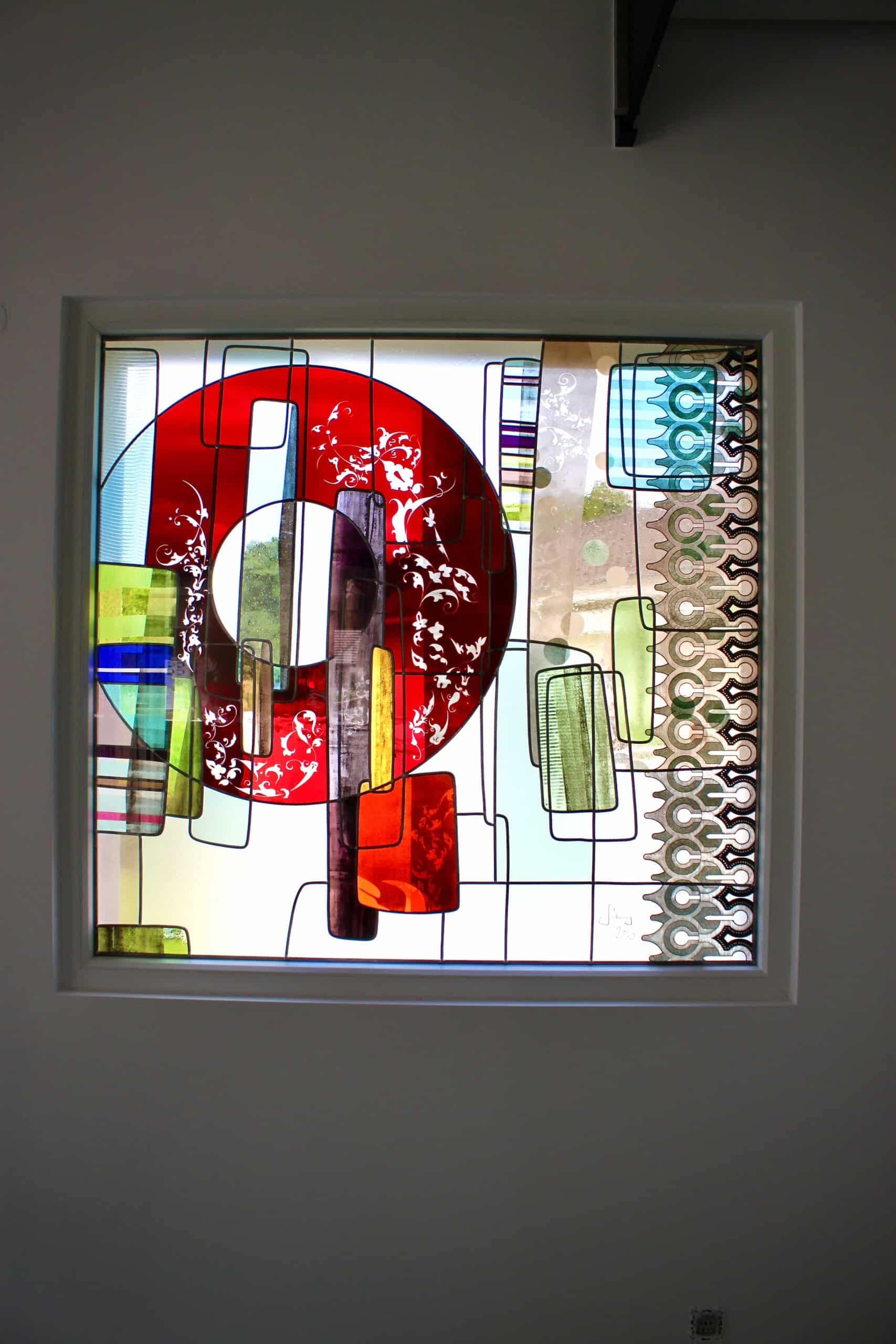 Vitrail contemporain au grand anneau rouge dans la fenêtre d’une cage d’escalier