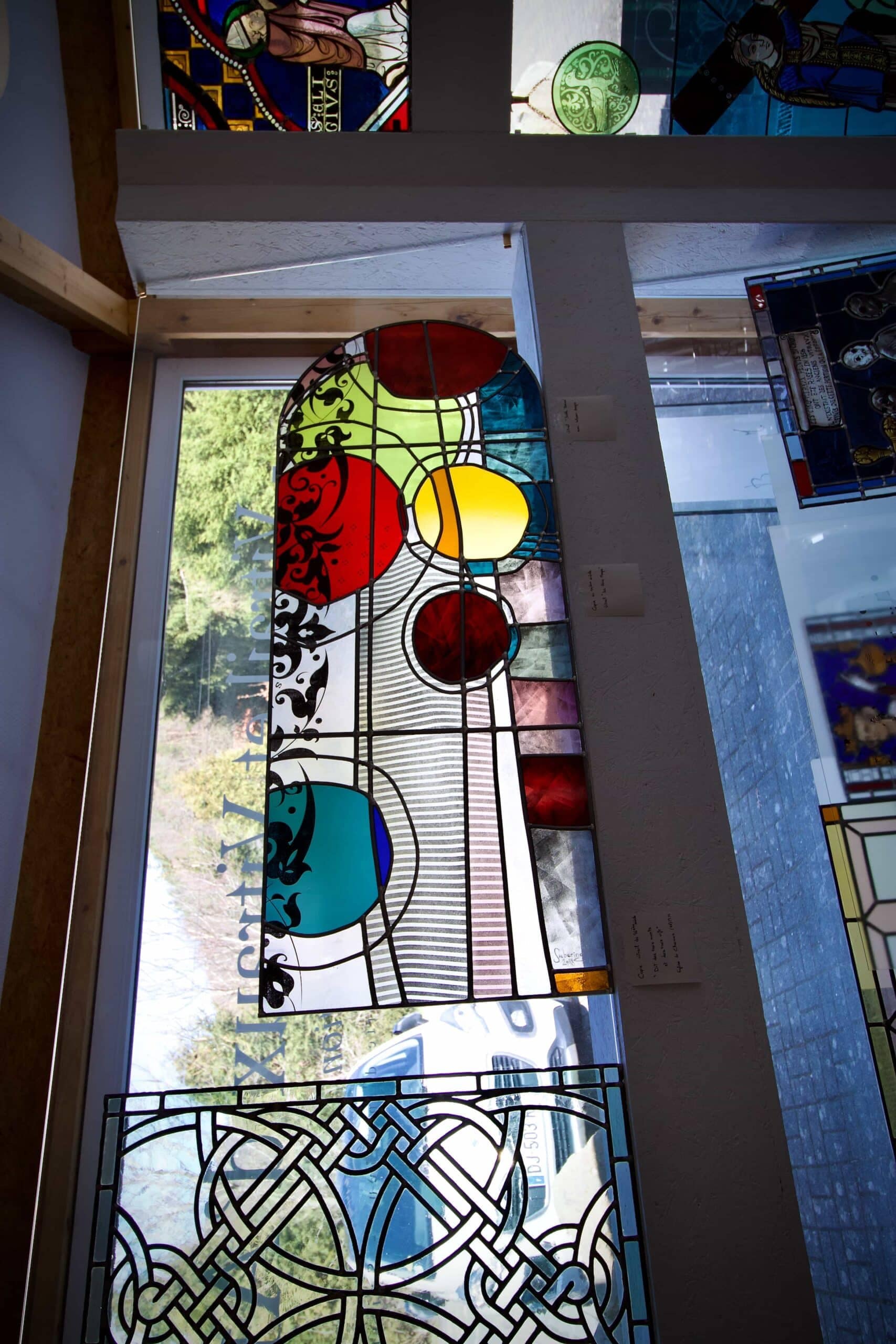 Vitrail abstrait vu sur toute sa hauteur, disques colorés sur un fond de bandes