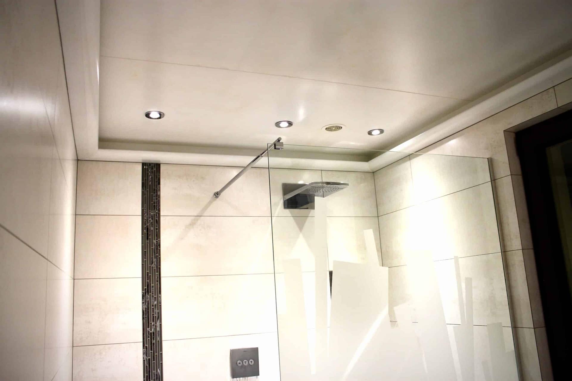 La douche et sa paroi en verre sous le plafond éclairé