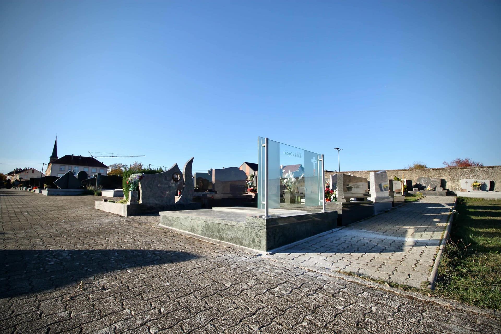 La tombe et sa stèle de verre dans l’allée du cimetière