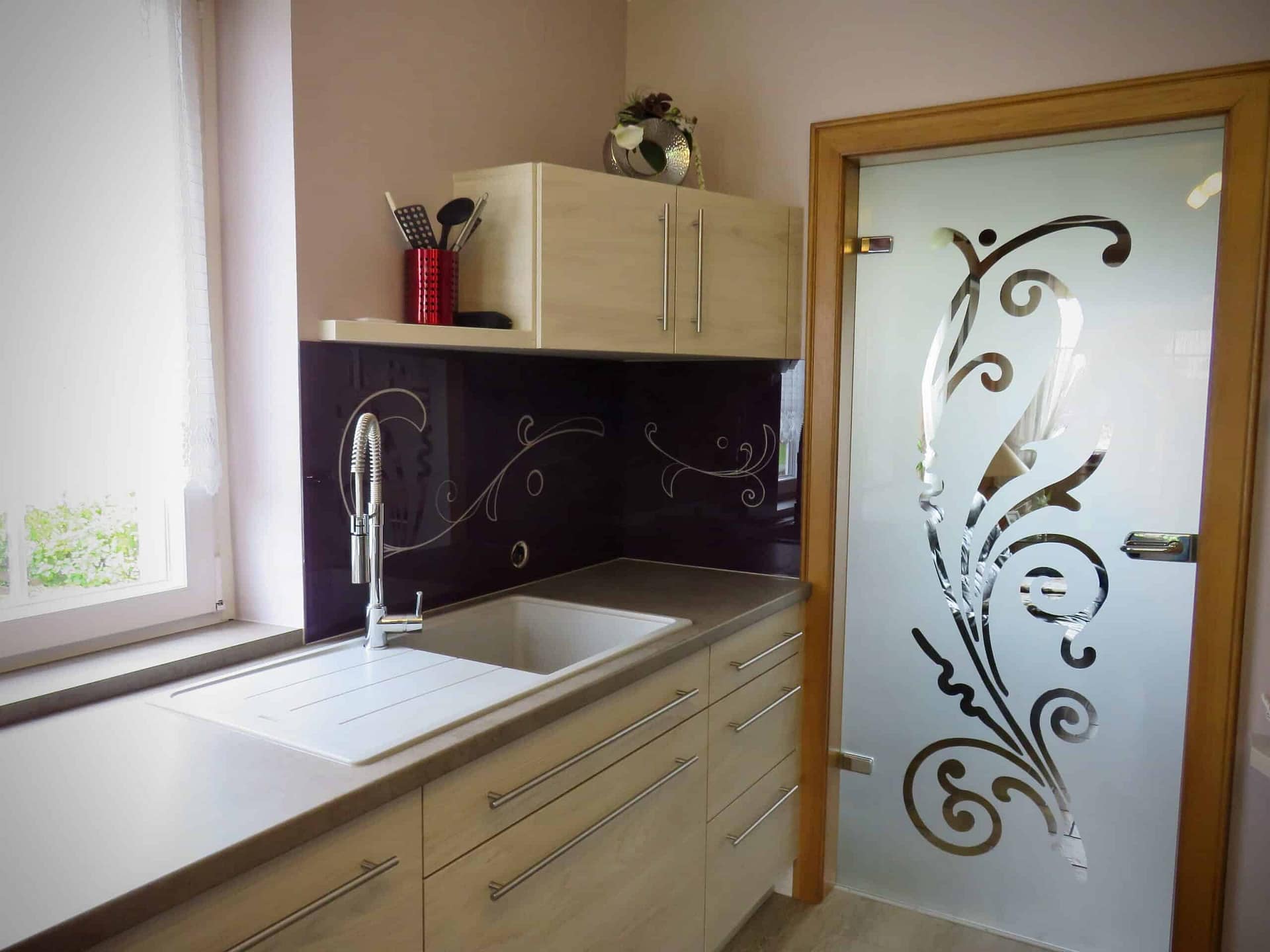 Porte en verre sablé à arabesques ouvrant sur une cuisine