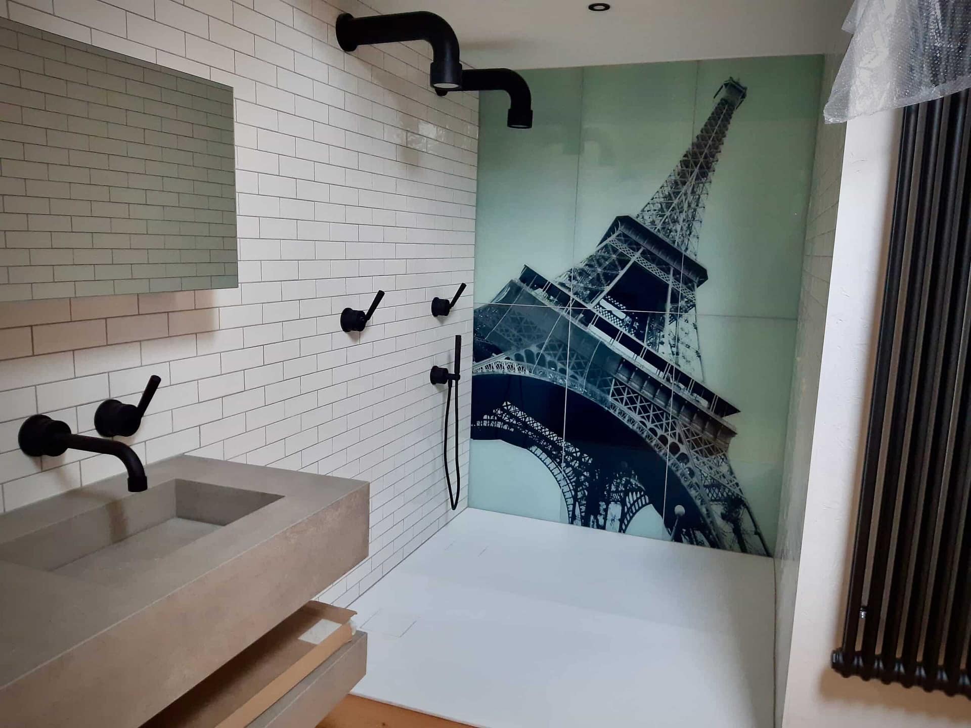 La douche, sa robinetterie noire et le décor du mur