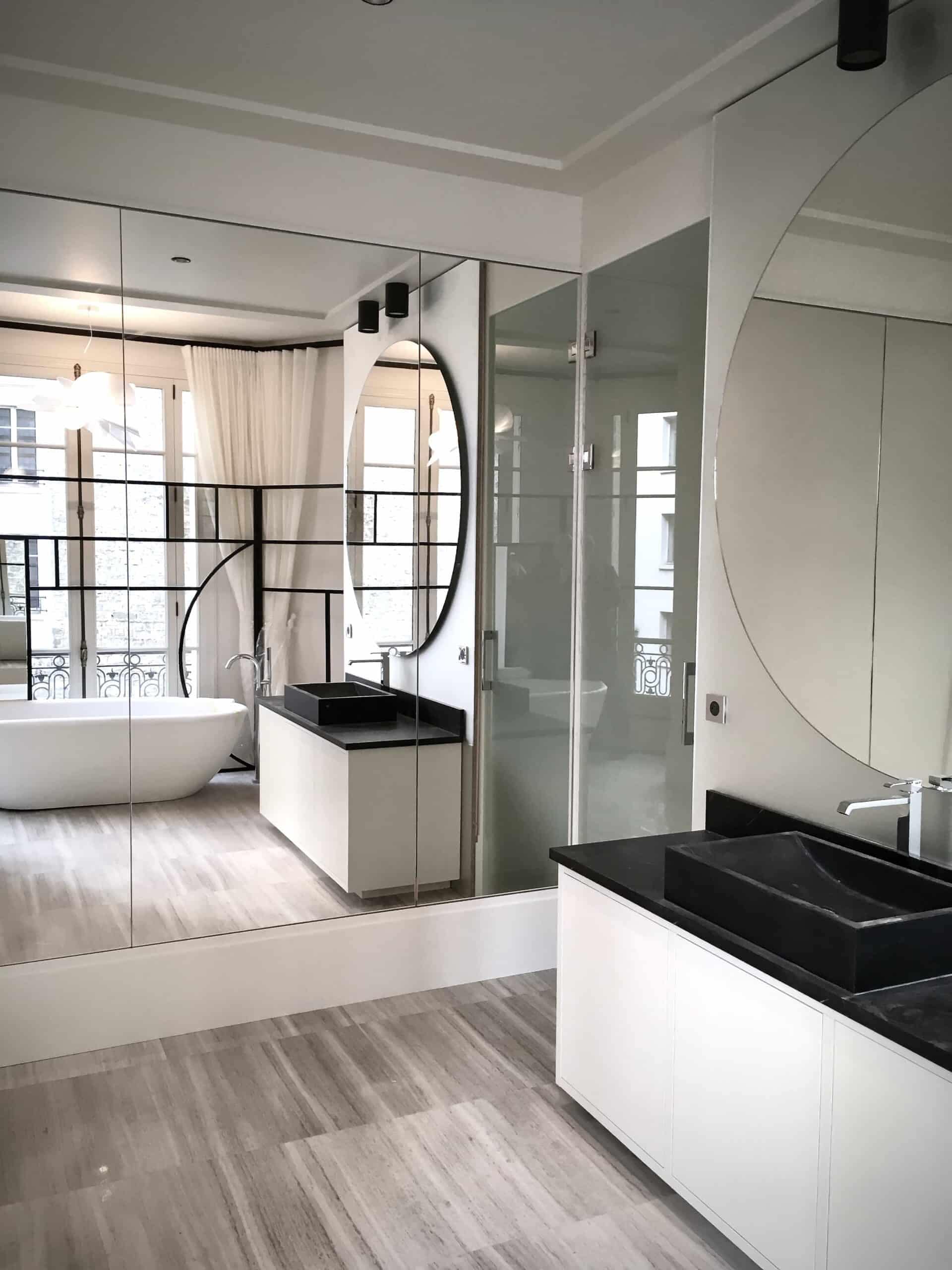 Salle de bains au grand miroir mural, au miroir rond et à la verrière à profilés noirs